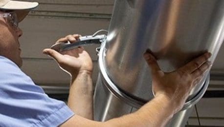 A man installing a cardboard dust duct.
